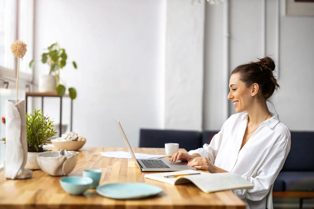 Une femme assise devant son bureau qui a des revenus complémentaires pour vivre d'internet